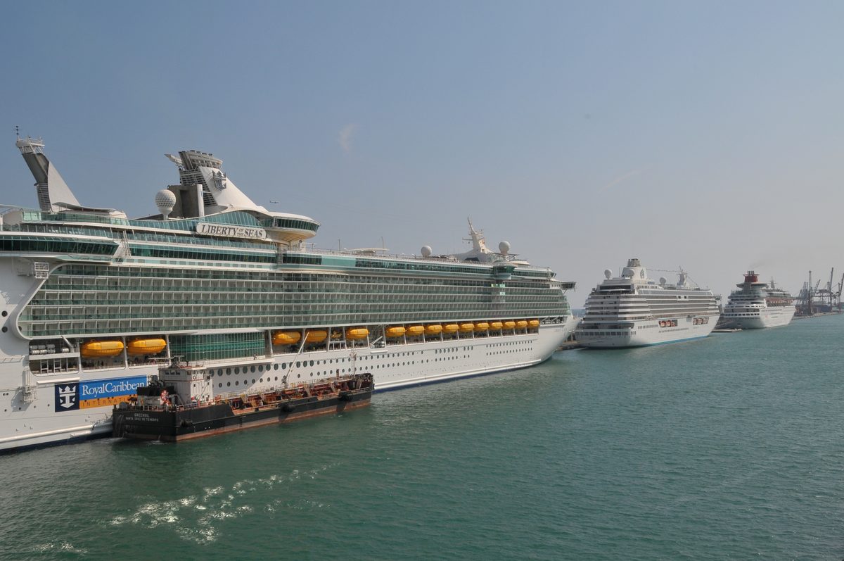 Hafen von Barcelona mit Segelbooten Mehrere Kreuzfahrtschiffe liegen im Hafen, darunter die Liberty of the Seas von Royal Caribbean im Vordergrund.